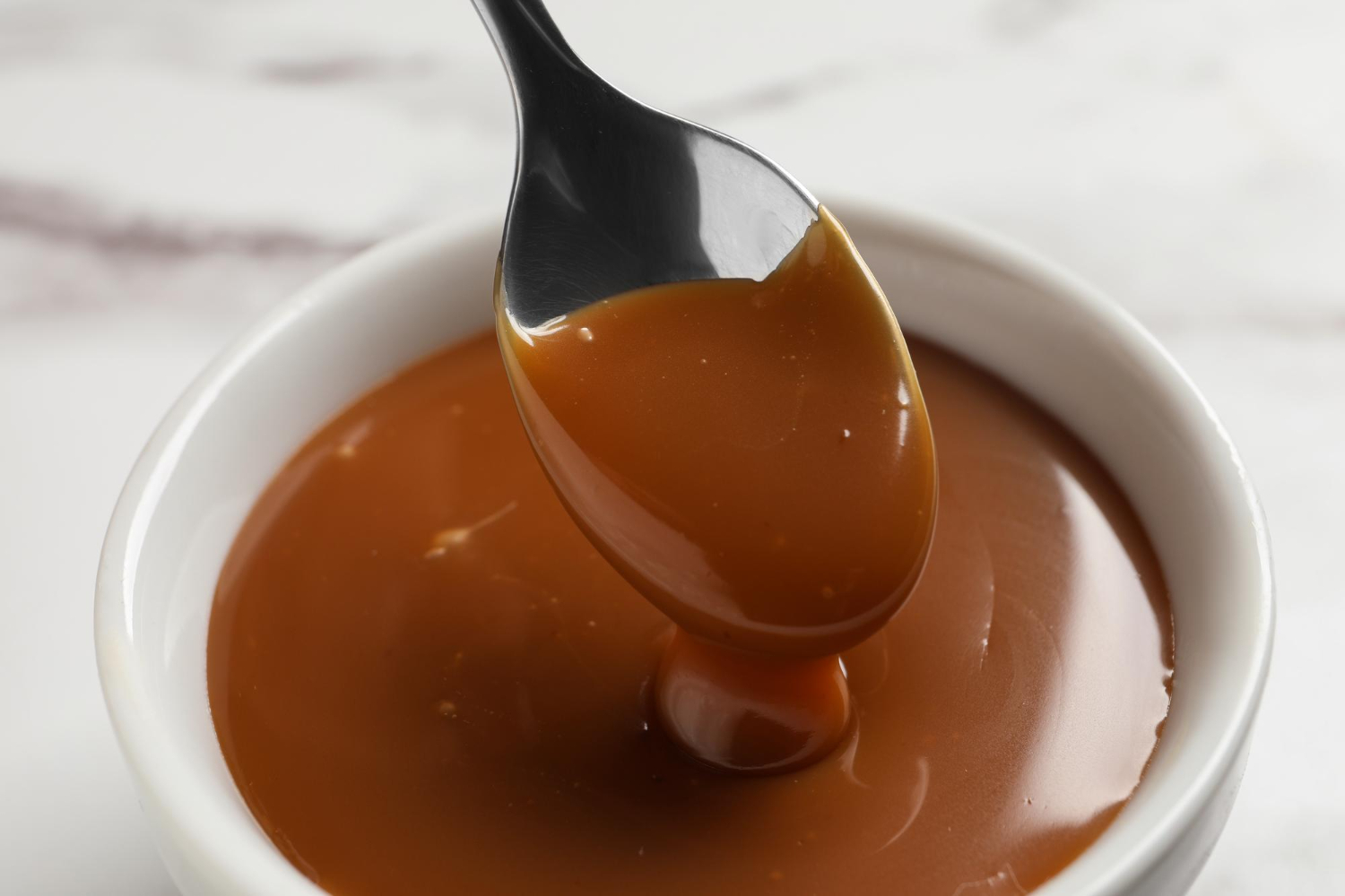 taking yummy salted caramel with spoon from bowl table closeup